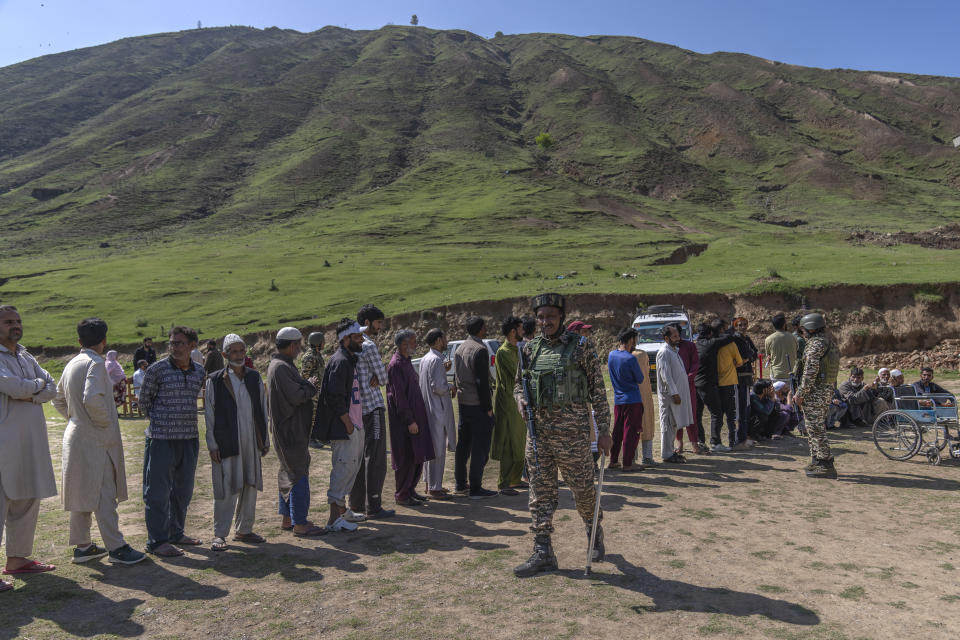 A paramilitary soldier stands guard near Kashmiri villagers who are queuing up to vote outside a polling booth during the fifth round of multi-phase national election in Rathson village, west of Srinagar, Indian controlled Kashmir, Monday, May 20, 2024. (AP Photo/Dar Yasin)