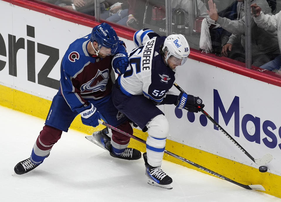 Winnipeg Jets center Mark Scheifele, right, tries to control the puck next to Colorado Avalanche defenseman Devon Toews during the first period of Game 3 of an NHL hockey Stanley Cup first-round playoff series Friday, April 26, 2024, in Denver. (AP Photo/David Zalubowski)