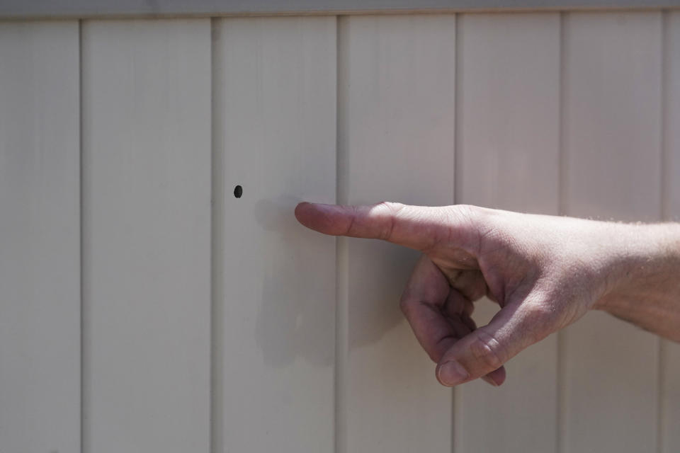 Lane Mugleston, the owner of Leap Ahead Daycare, points to a bullet hole as he speaks to reporters Tuesday, May 23, 2023, in Spanish Fork, Utah. A 2-year-old boy was shot in the head by a stray bullet while playing outside at day care in Utah, the facility's owner and authorities said. Spanish Fork police believe the bullet came from a pellet or air gun shot from a farming field across the street west of the facility, Lt. Clay Slaymaker said. (AP Photo/Rick Bowmer)