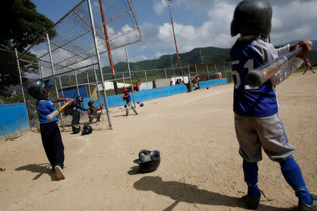 Children play during a baseball championship in Caracas, Venezuela August 24, 2017. REUTERS/Carlos Garcia Rawlins/Files