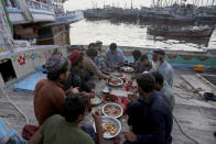 Fishermen break their fast during the Muslim holy fasting month of Ramadan, on a boat in a dockyard, in Karachi, Pakistan, Tuesday, April 20, 2021. (AP Photo/Fareed Khan)