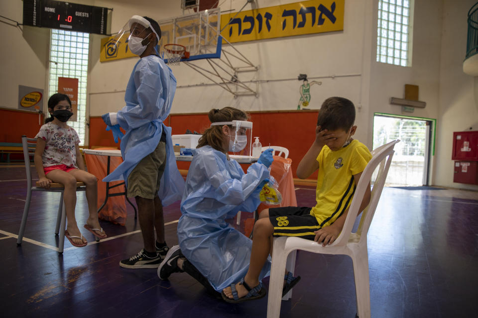 Medical personnel test Israeli children the coronavirus at a basketball court turned into a coronavirus testing center, in Binyamina, Israel, Tuesday, June 29, 2021. Israel's prime minister is urging the country's youth to get vaccinated as coronavirus case numbers have crept up in recent days due to a localized outbreak of the Delta variant. (AP Photo/Ariel Schalit)