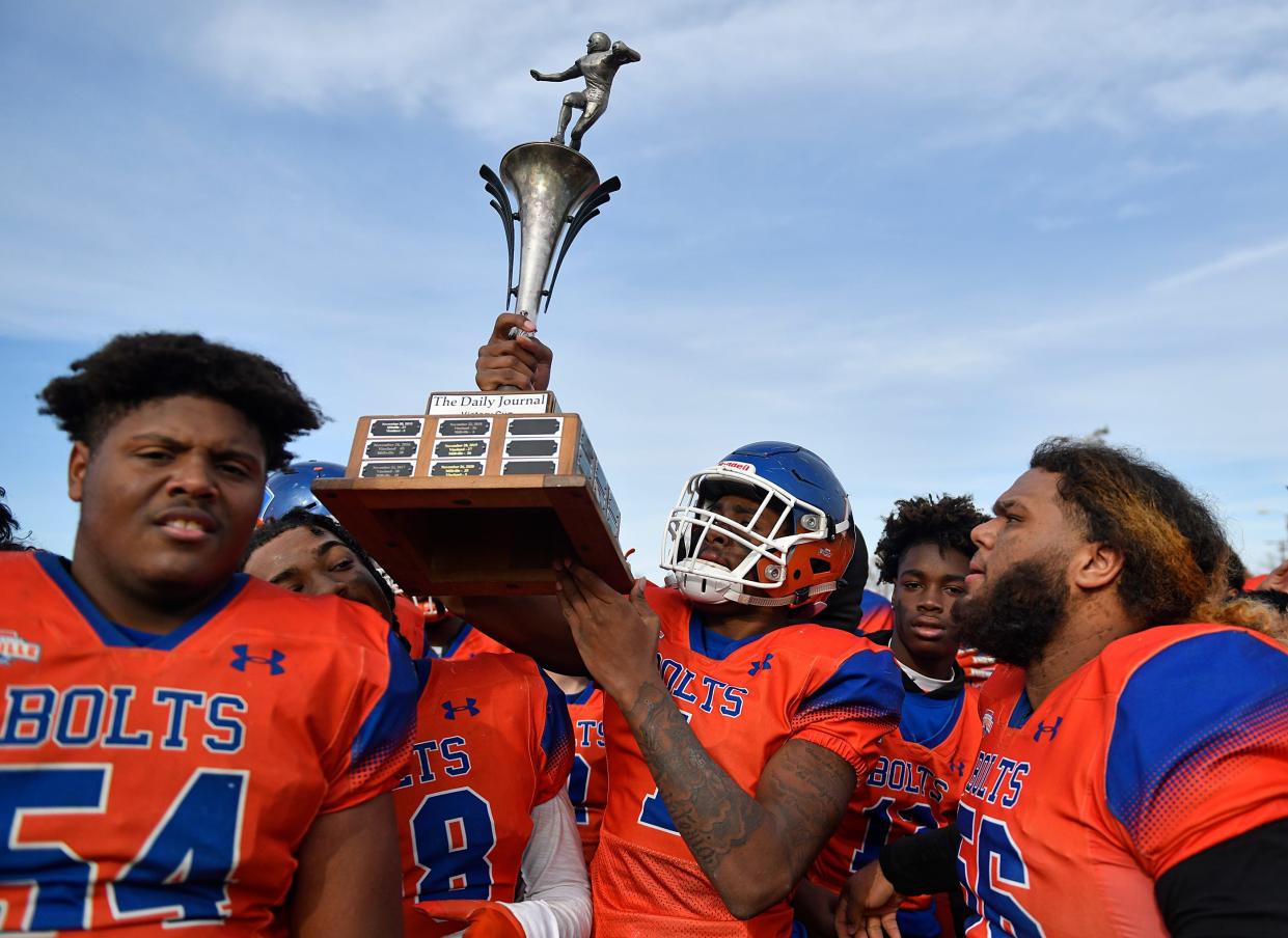 Millville's LeQuint Allen (1) holds up The Daily Journal Victory Cup after defeating Vineland 47-0 at Wheaton Field on Thanksgiving Day. Nov. 25, 2021.