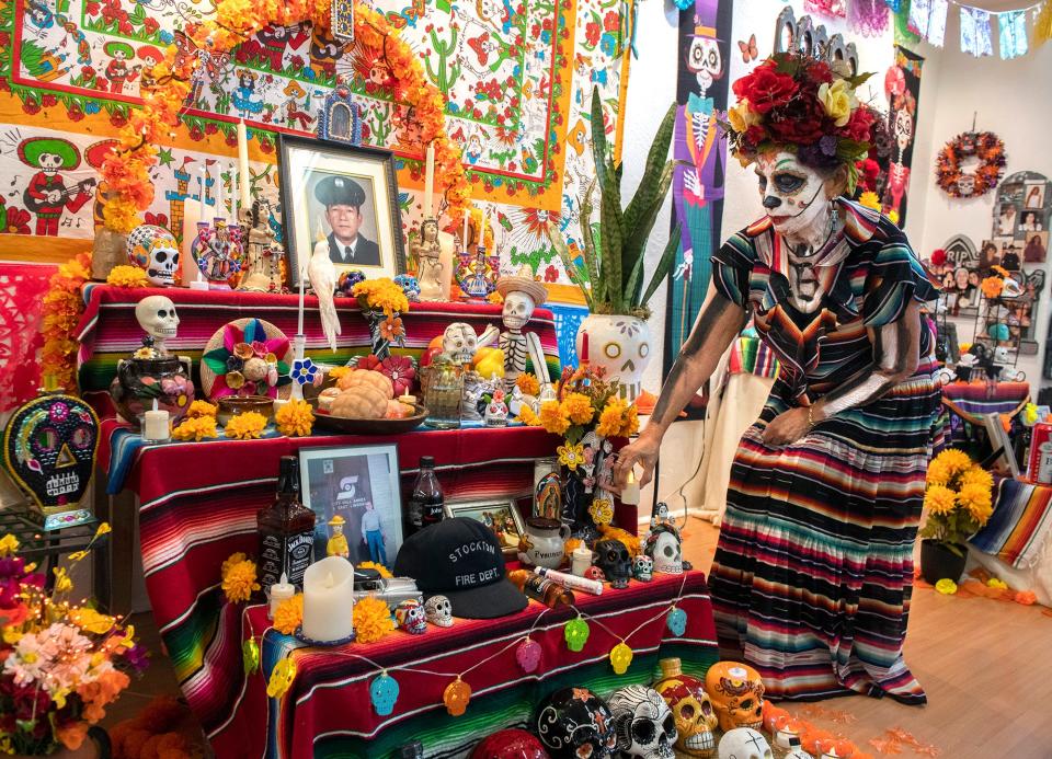 Yolanda Laguna puts the finishing touches on her ofrenda in honor of her late husband John at the annual Dia De Los Muertos Community Street Fiesta at the Mexican Heritage Center in downtown Stockton on Saturday, Oct. 29, 2022. 
