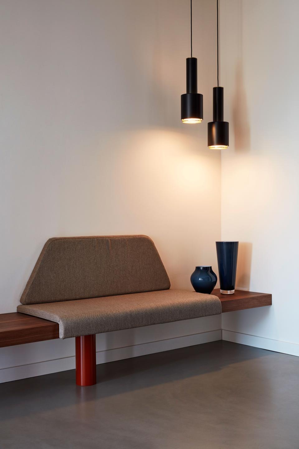 At the entrance, a cozy nook is furnished with a small bespoke bench and adorned with two pendants by Artek.