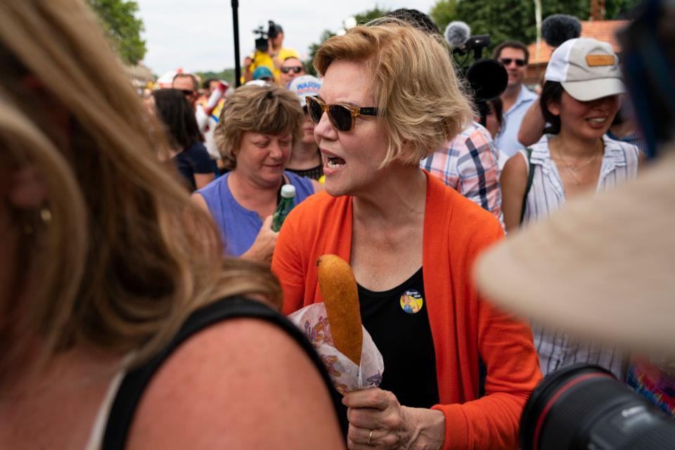 Warren holds a corn dog as she chats with fair attendees on Aug. 10.