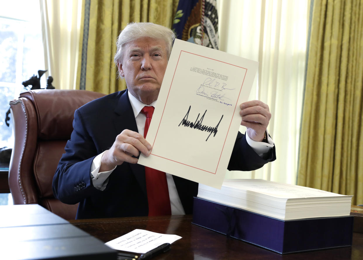 President Trump shows off the tax bill after signing it on Dec. 22. (Photo: Evan Vucci/AP)