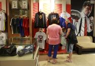 A couple look at souvenir items of boxer Manny Pacquiao of the Philippines that are displayed for sale, inside a store in metro Manila April 24, 2015. Sales of Manny Pacquiao boxing gear and effects have soared as much as 10 times ahead of his May 2 megafight with Floyd Mayweather, with Philippine retailers struggling to cope with demand from fans snapping up any paraphernalia they could find. Online and front-end retailers are seeing record sales of Pacquiao T-shirts, boxing gloves, figurines, caps and jackets, with buyers stocking up on items they believe could at least double in value if he wins what is seen as the highest grossing bout in history. Picture taken April 24. REUTERS/Romeo Ranoco