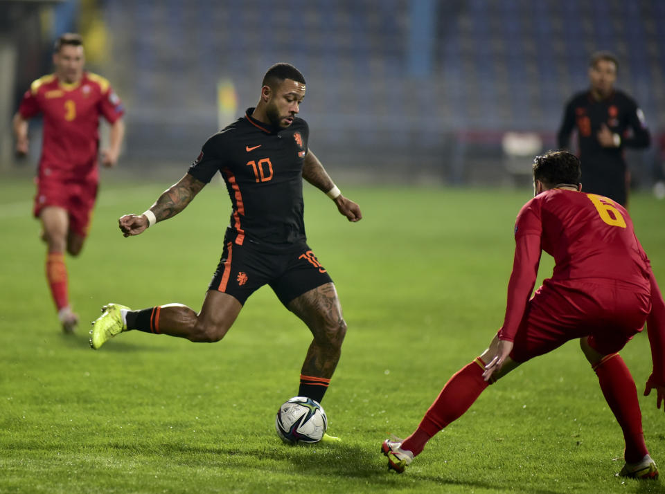 Netherlands' Memphis Depay, left, duels for the ball with Montenegro's Igor Vujacic during the World Cup 2022 group G qualifying soccer match between Montenegro and Netherlands, at the City stadium in Podgorica, Montenegro, Saturday, Nov. 13, 2021. (AP Photo/Risto Bozovic)