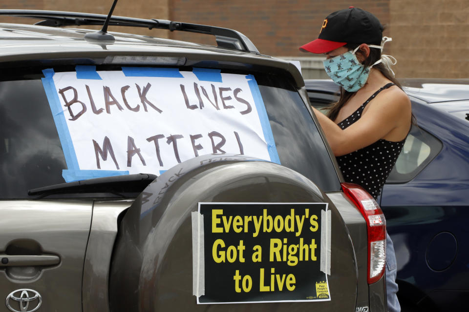 Amalia Kalisz Tonsor, of Pittsburgh, decorates a vehicle in the parking lot of a Shop & Save in downtown Pittsburgh as part of the Pennsylvania Poor People's Campaign: National Call for Moral Revival, Sunday, June 14, 2020. The caravan circled various government offices in Pittsburgh. (AP Photo/Gene J. Puskar)