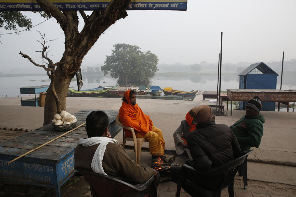 People sit by a bonfire in the morning on the banks of the River Gomati in Lucknow, Uttar Pradesh state, India, Sunday, Dec. 22, 2019. Violent protests against India's citizenship law that excludes Muslim immigrants have swept the country over the weekend despite the government's ban on public assembly and suspension of internet services in many parts. Police said nine people died in clashes with security forces in Uttar Pradesh on Saturday, most of them young protesters. (AP Photo/Rajesh Kumar Singh)