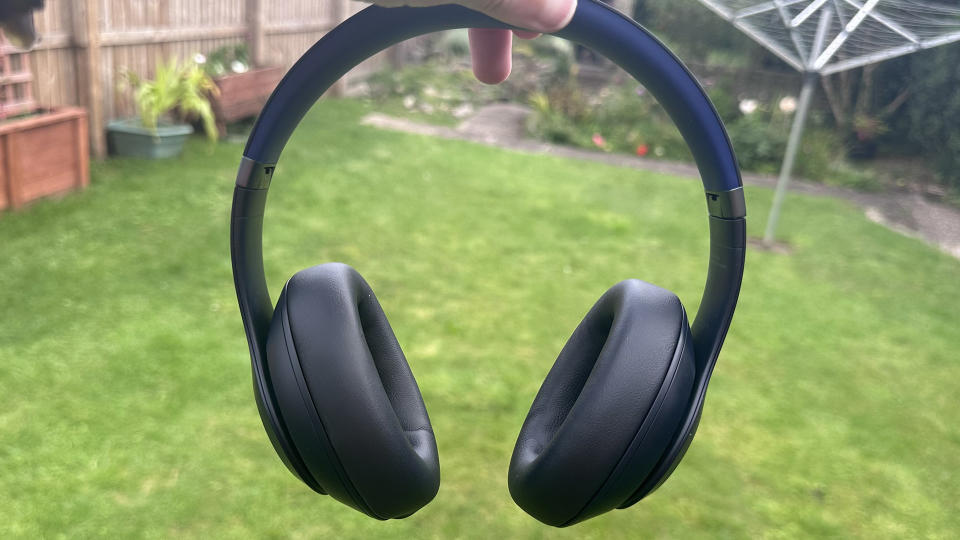 Someone holding the Beats Studio Pro over-ear headphones in black above grass.