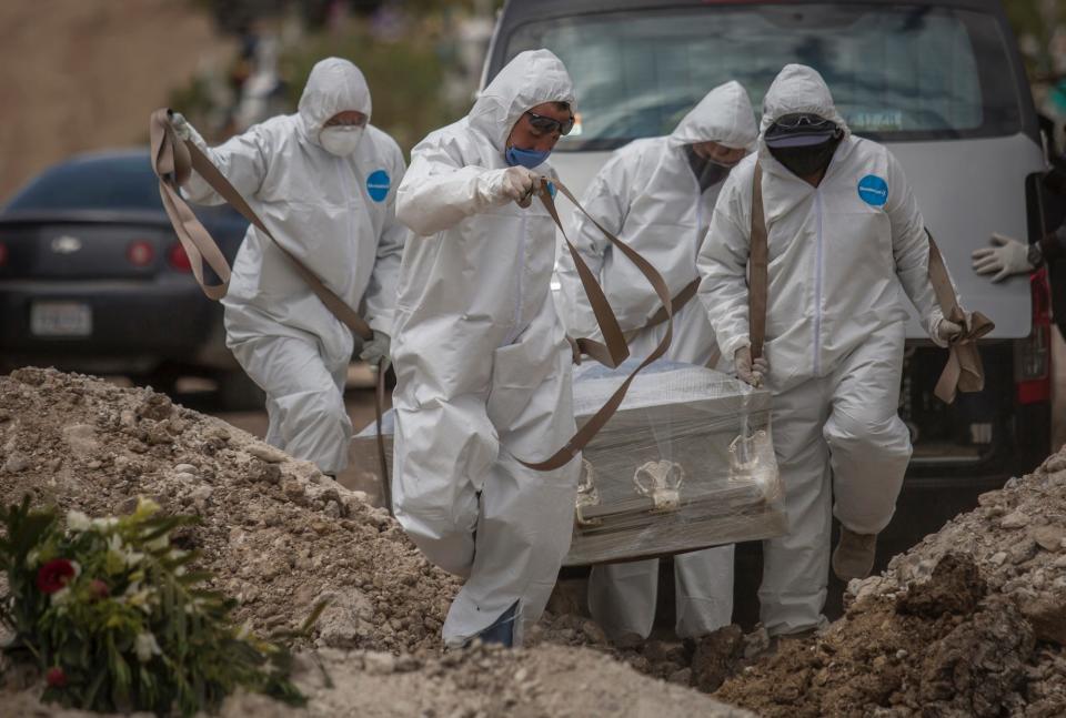 Workers in protective suits carrying a coffin in a cemetery during the Covid 19 pandemic in Mexico.