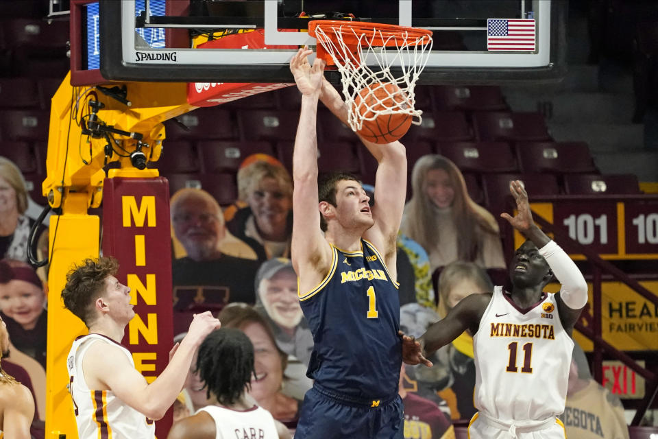 Michigan's Hunter Dickinson (1) dunks as Minnesota's Liam Robbins, left, Marcus Carr and Both Gach, right, watch during the first half an NCAA college basketball game, Saturday, Jan. 16, 2021, in Minneapolis. (AP Photo/Jim Mone)