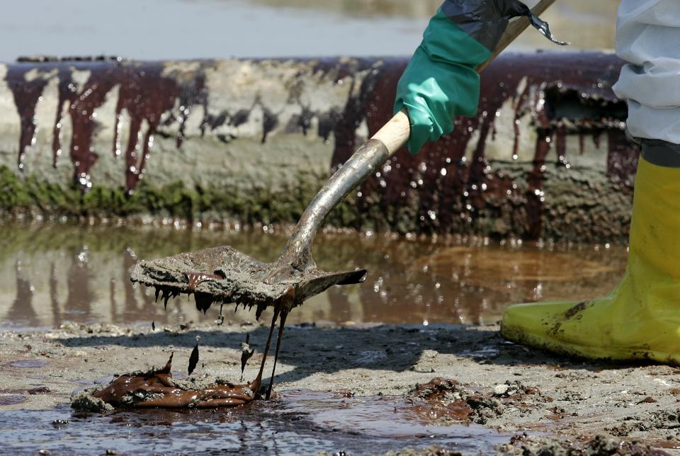 FILE - A worker shovels oil from the Deepwater Horizon oil spill off Fourchon Beach in Port Fourchon, La., May 24, 2010. When a deadly explosion destroyed BP's Deepwater Horizon drilling rig in the Gulf of Mexico, tens of thousands of ordinary people were hired to help clean up the environmental devastation. These workers were exposed to crude oil and the chemical dispersant Corexit while picking up tar balls along the shoreline, laying booms from fishing boats to soak up slicks and rescuing oil-covered birds. (AP Photo/Patrick Semansky, File)