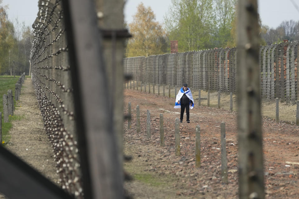 A man walks covered by Israeli flag at the Auschwitz Nazi concentration camp after the March of the Living annual observance that was not held for two years due to the global COVID-19 pandemic, in Oswiecim, Poland, Thursday, April 28, 2022. Only eight survivors and some 2,500 young Jews and non-Jews are taking part in the annual march that is scaled down this year because of the war in neighboring Ukraine that is fighting Russia's invasion. (AP Photo/Czarek Sokolowski)