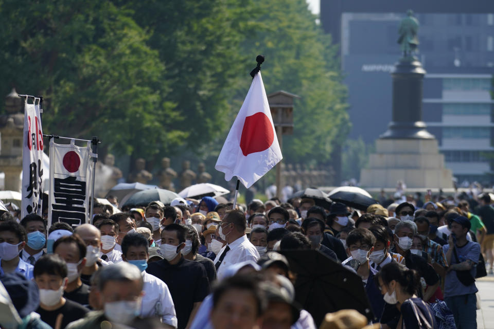 Worshippers queue to pay respects to the war dead at Yasukuni Shrine Saturday, Aug. 15, 2020, in Tokyo. Japan marked the 75th anniversary of the end of World War II. (AP Photo/Eugene Hoshiko)