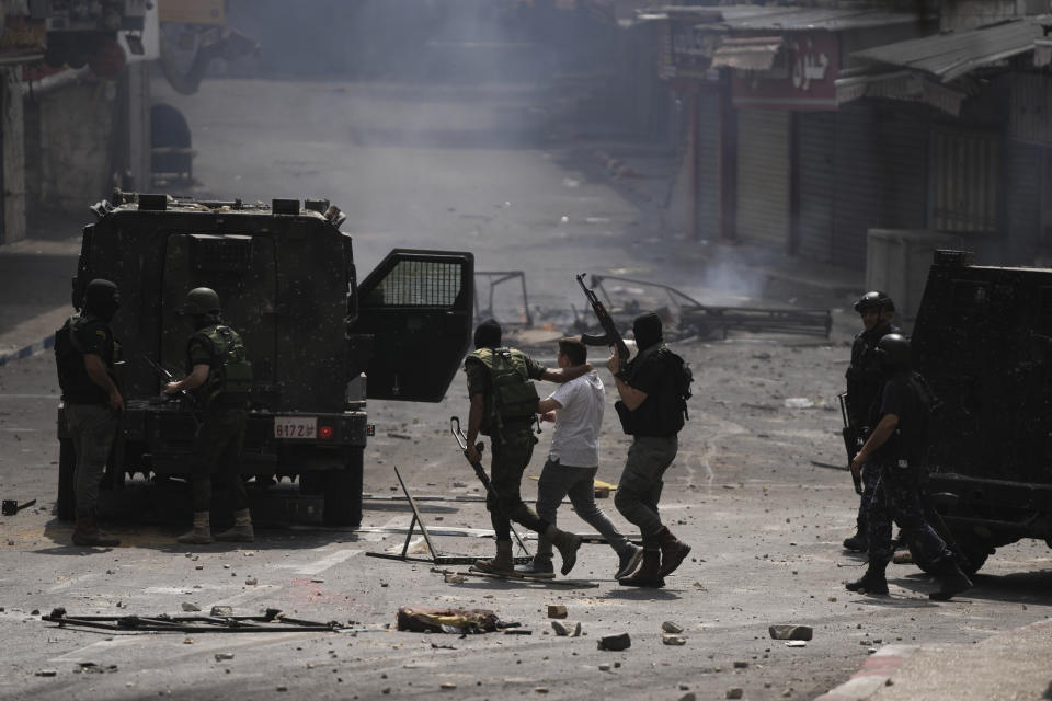 Palestinian security forces detain a Palestinian protester during clashes following an arrest raid against local militants, in the West Bank city of Nablus Tuesday, Sept. 20, 2022. Palestinian security forces on Tuesday exchanged fire with militants in the center of the West Bank's second-largest city, as angry residents pelted an armored jeep with objects and chased it away. One man was reported dead. The incident, sparked by an arrest raid against local militants, marked a rare case of deadly internal Palestinian fighting in the occupied West Bank. (AP Photo/Nasser Nasser)