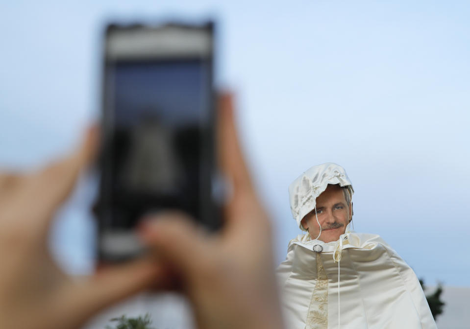 A woman takes a picture of a cardboard depiction of Liviu Dragnea, the leader of the ruling Social Democratic party, as hundreds celebrate his sentencing to prison outside the government headquarters in Bucharest, Romania, Monday, May 27, 2019. Romania's most powerful politician was sentenced Monday to 3 and a half years in prison for official misconduct in a graft case. (AP Photo/Nicolae Dumitrache)