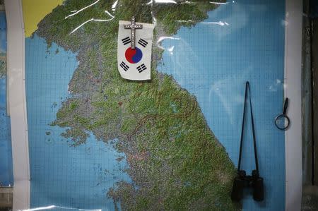 A cross and South Korean flag are hung on North Korean areas of the map of the Korean peninsula at the home of North Korean defector Lee Min-bok in Pocheon, about 15 km (9 miles) south of the demilitarized zone separating the two Koreas, October 15, 2014. REUTERS/Kim Hong-Ji