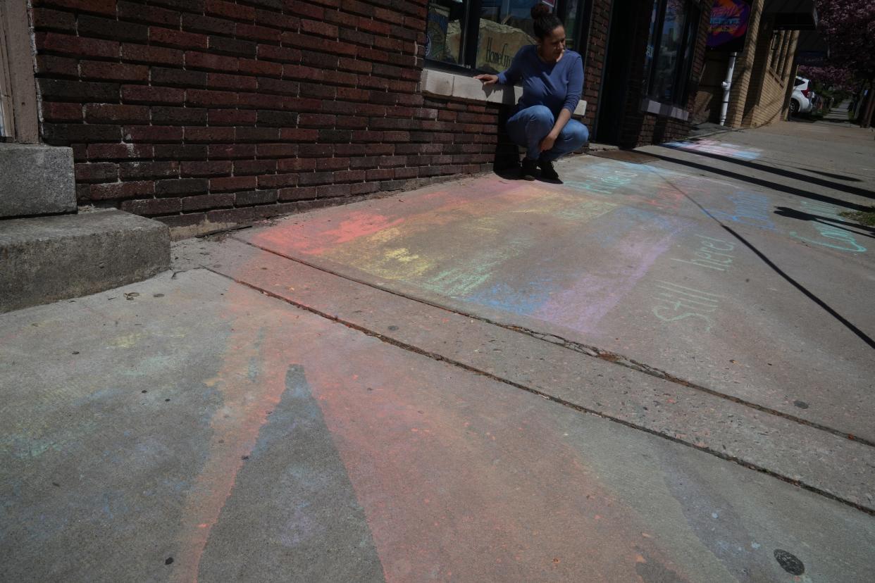 Mildred Concha of Heavenly Juicin’ looks at a chalk drawing that she said was partially washed away by someone attempting to erase it. It was redrawn with a defiant "Still here!"