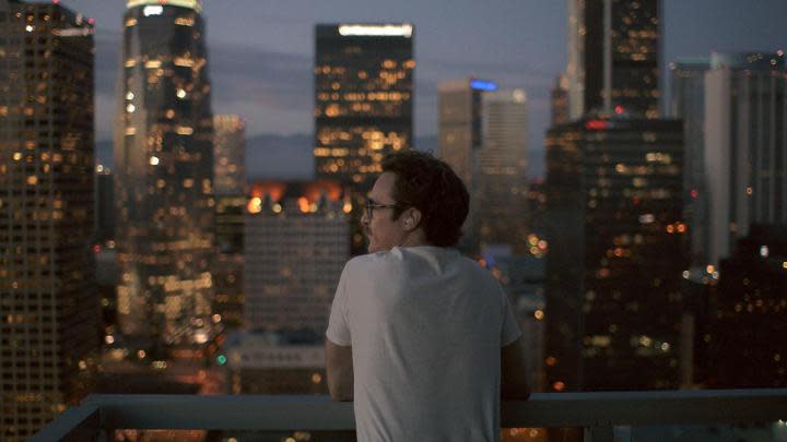 Joaquin Phoenix looking at a cityscape on his balcony in Her.