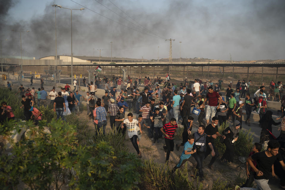 Palestinian protesters run from tear gas fired by Israeli soldiers during a protest at the entrance of Erez border crossing between Gaza and Israel, in the northern Gaza Strip, Tuesday, Sept. 4, 2018. The Health Ministry in Gaza says several Palestinians were wounded by Israeli fire as they protested near the territory's main personnel crossing with Israel. (AP Photo/Felipe Dana)