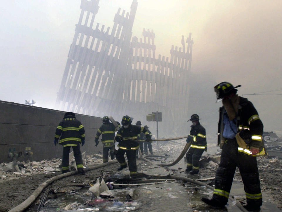 <p>Firefighters work beneath the destroyed mullions, the vertical struts, of the World Trade Center in New York on Tuesday, Sept. 11, 2001. (AP Photo/Mark Lennihan)</p> 