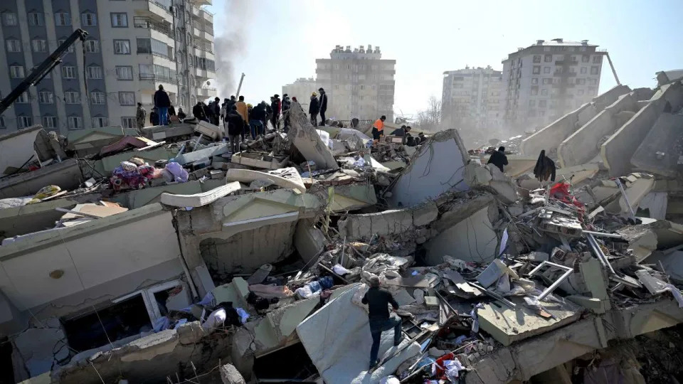 Families of victims stand as rescue officials search among the rubble of collapsed buildings in Kahramanmaras, on February 9, 2023, three days after a 7,8-magnitude earthquake struck southeast Turkey. - The death toll from a huge earthquake that hit Turkey and Syria climbed to more than 17,100 on February 9, as hopes faded of finding survivors stuck under rubble in freezing weather. (Photo by OZAN KOSE / AFP)