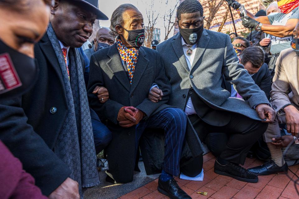 Attorney Benjain Crump (left), the Rev. Al Sharpton and George Floyd's family members kneel outside the courthouse on the opening day of the trial of former Minneapolis police officer Derek Chauvin Monday. (Kerem Yucel/AFP via Getty Images)