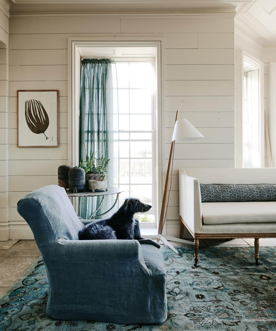 living room with blue linen armchair and linen curtains and antique sofa upholstered in linen with blue rug