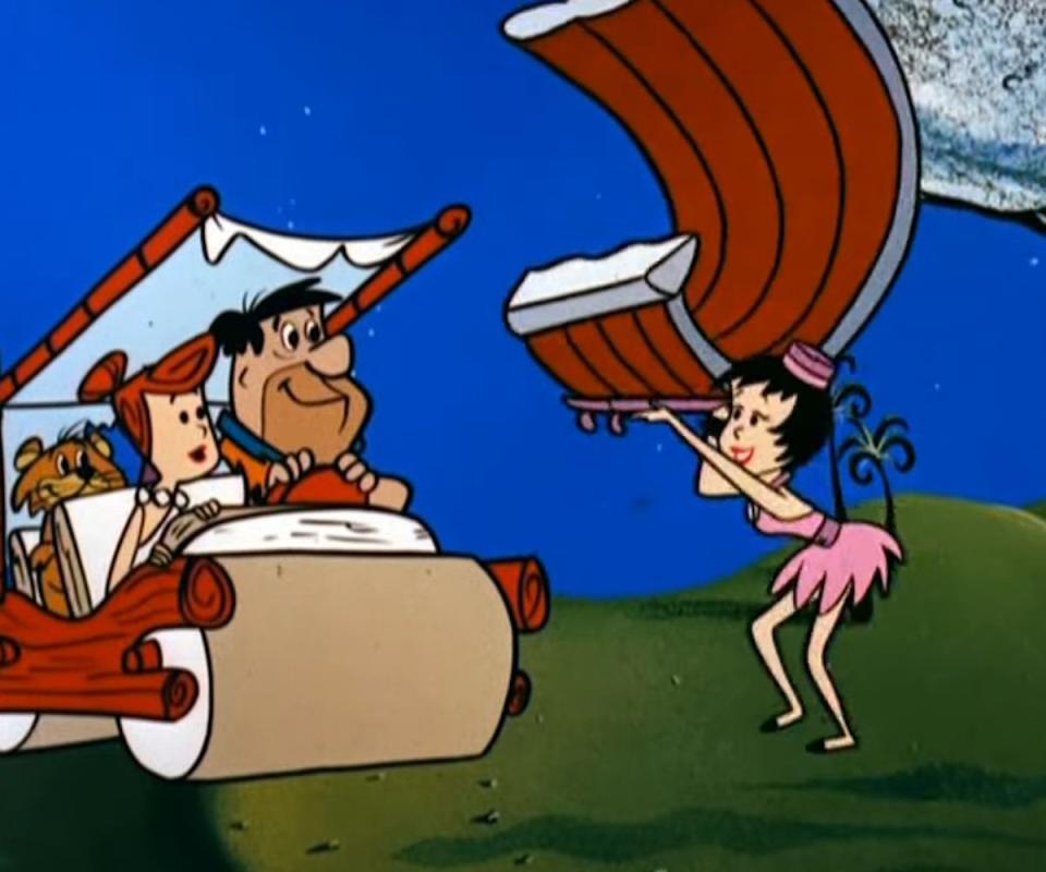 The Flintstones watch a waitress bring them giant Brontosaurus ribs