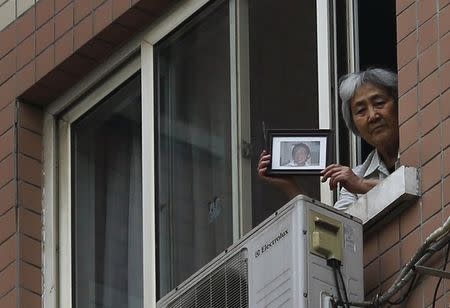 Zhang Xianling, whose son Wang Nan was killed by soldiers at the Tiananmen Square in 1989, holds his picture after journalists were turned away, at the window of her home in Beijing, April 24, 2014. REUTERS/Petar Kujundzic