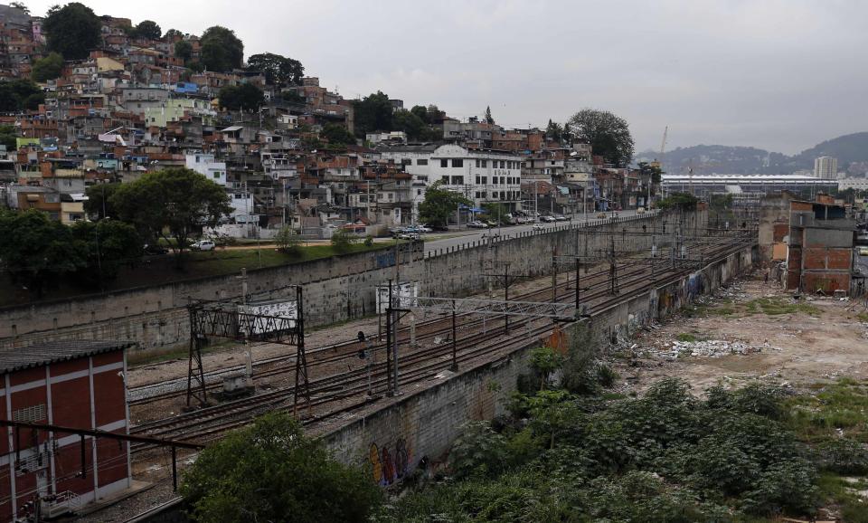 The Metro Mangueira slum (R), which will be demolished for the 2014 World Cup infrastructure, is seen next to the Mangueira slum (L) and near the Maracana stadium in Rio de Janeiro March 25, 2014. According to a document released by the popular movement "Comite Popular da Copa e Olimpiadas do Rio de Janeiro" (People's Committee of the World Cup and Olympic Games in Rio de Janeiro), the preparations for the 2014 World Cup and the 2016 Olympic Games in Rio de Janeiro will displace more than 7,185 families from their homes to make way for new sports facilities, bus routes for traffic and improvements in tourism infrastructure. REUTERS/Sergio Moraes (BRAZIL - Tags: SOCIETY SPORT SOCCER)