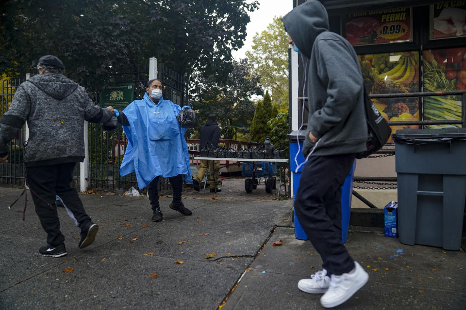 Volunteer Dawn Cherry, center, hands out boxed meals prepared at the South Bronx restaurant La Morada, Wednesday Oct. 28, 2020, in New York. After a fund raising campaign during the coronavirus pandemic, La Morada, an award winning Mexican restaurant, reopened and now also functions as a soup kitchen, serving 650 meals daily. (AP Photo/Bebeto Matthews)