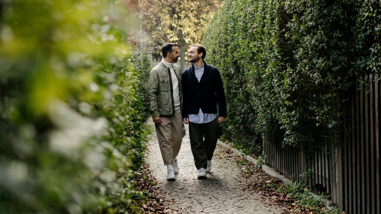  two men walking hand in hand in a park 