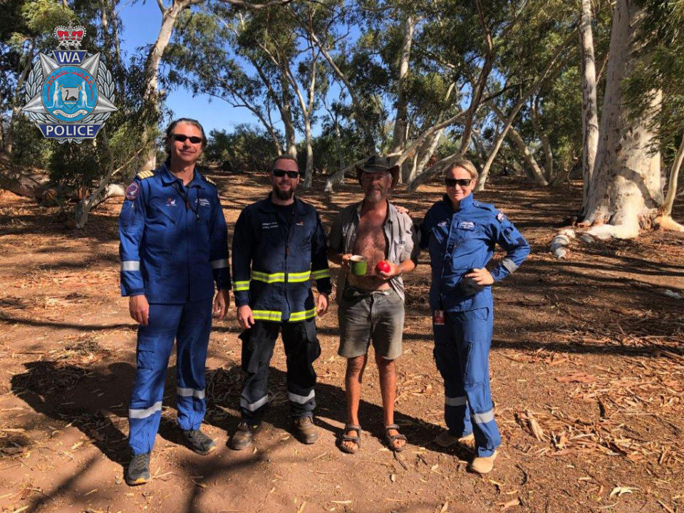 Phillip Blampied with some of his rescuers standing among trees.