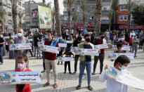 Hamas supporters wear face masks while holding placards during a protest against French President Emmanuel Macron and the publishing of caricatures of the Muslim Prophet Muhammad they deem blasphemous, at the main road of Jebaliya refugee camp, Gaza Strip, Friday, Oct. 30, 2020. Arabic reads: "Despite Macron's malice, we rise up to our Prophet", "I sacrifice myself, my father and mother for you Prophet." And "Boycott French products in support for our Prophet Mohammed." (AP Photo/Adel Hana)