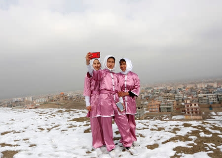 Latifa Safay (R), 15, Hanifa Doosti (C), 17, and Suraya Rezai, 19, students of the Shaolin Wushu club, take a selfie before practicing on a hilltop in Kabul, Afghanistan January 29, 2017. REUTERS/Mohammad Ismail