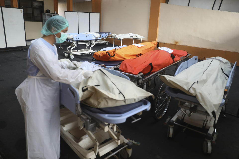 A medical worker puts identification tag on the bodies of the victims of a soccer stampede at the Saiful Anwar Hospital in Malang, East Java, Indonesia, Sunday, Oct. 2, 2022. Panic at an Indonesian soccer match after police fired tear gas to to disperse supporters invading the pitch left over 100 people dead, mostly trampled to death, police said Sunday. (AP Photo/Trisnadi)