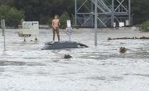 Young man crossed dangerous flood waters in Toombul. Photo: Twitter/Trenton Akers