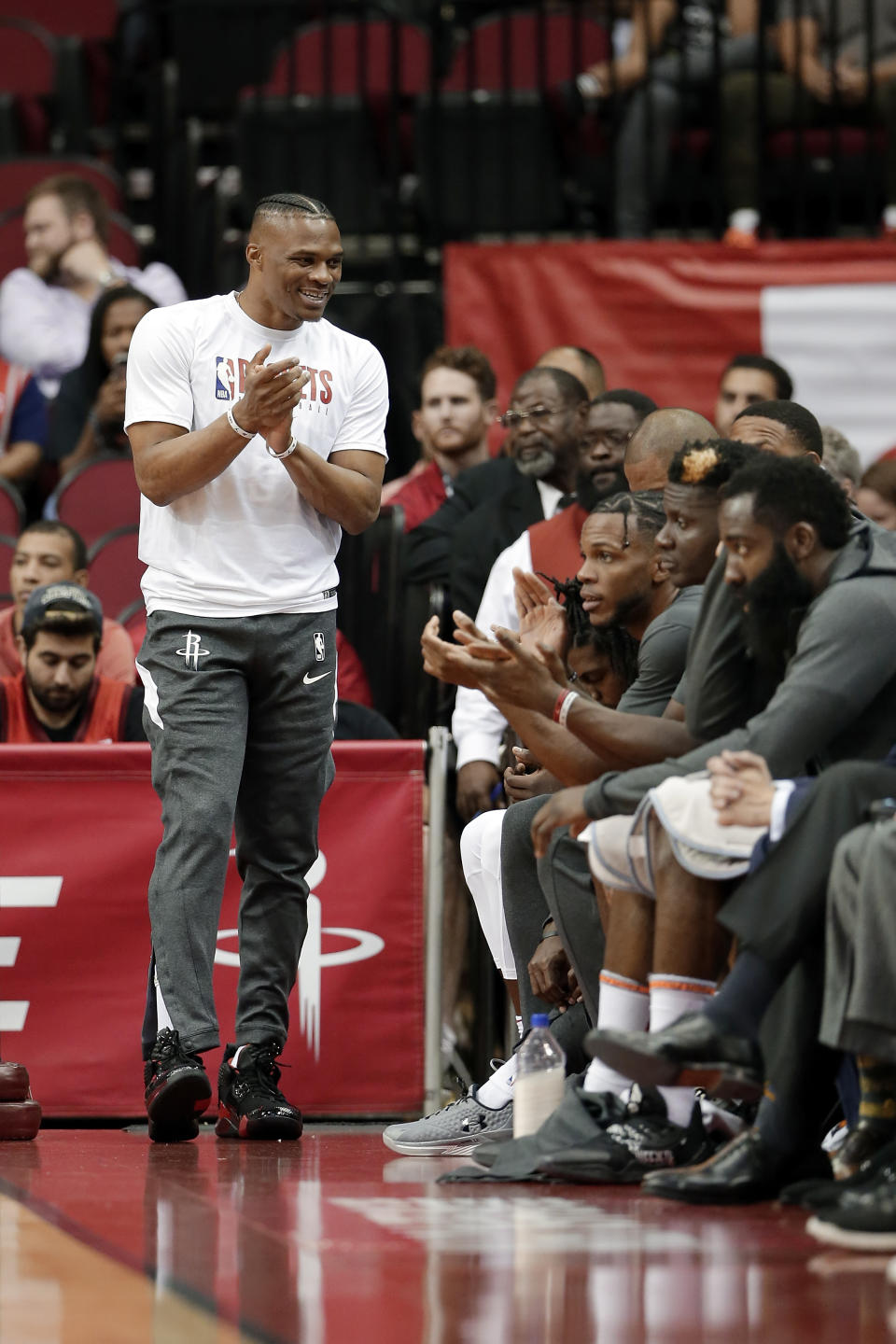 Houston Rockets guard Russell Westbrook, left, celebrates a score from the bench as he sits out an NBA basketball preseason game against the Shanghai Sharks during the first half Monday, Sept. 30, 2019, in Houston. (AP Photo/Michael Wyke)