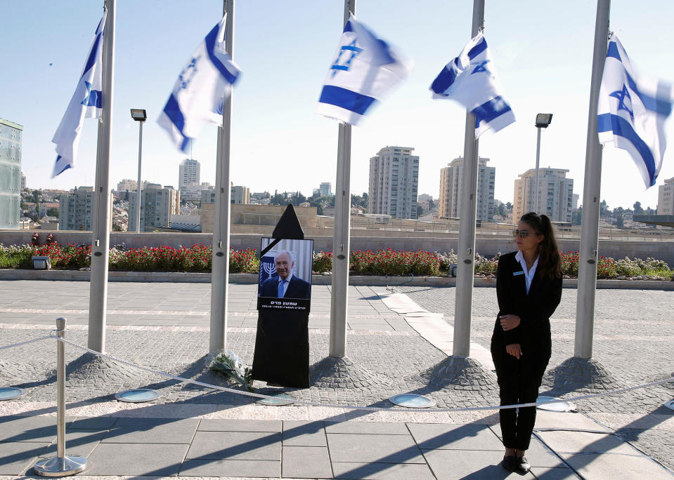 <p>A woman stands next to Israeli flags lowered to half mast near a portrait of former Israeli President Shimon Peres, as he lies in state at the Knesset plaza, the Israeli parliament, in Jerusalem on Sept. 29, 2016. (REUTERS/Amir Cohen) </p>