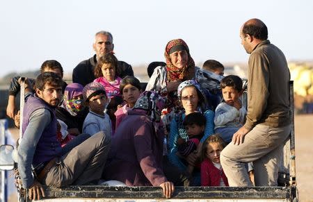 Newly arrived Syrian Kurdish refugees stand at the back of a truck after crossing into Turkey from the Syrian border town Kobani, near the southeastern Turkish town of Suruc in Sanliurfa province October 6, 2014. REUTERS/Umit Bektas