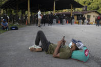 Un migrante hondureño descansa ante un bloqueo de carretera impuesto por las fuerzas de seguridad en Poptun, Guatemala, el 2 de octubre de 2020. (AP Foto/Moisés Castillo)