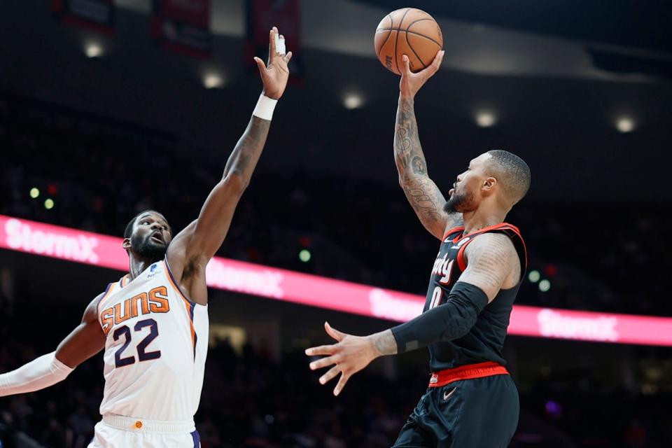 Dec 14, 2021; Portland, Oregon, USA; Portland Trail Blazers point guard Damian Lillard (0) shoots the ball over Phoenix Suns center Deandre Ayton (22) during the second half at Moda Center. Mandatory Credit: Soobum Im-USA TODAY Sports.