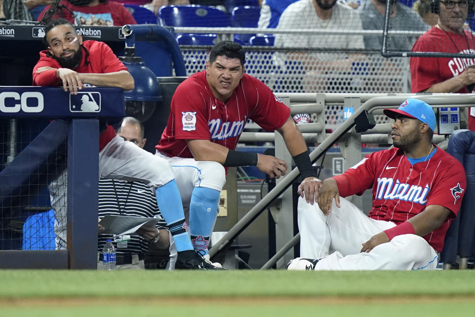 Miami Marlins' Billy Hamilton, left, Avisail Garcia, center, and Jesus Aguilar watch from the dugout during the ninth inning of the team's baseball game against the Philadelphia Phillies, Saturday, July 16, 2022, in Miami. The Phillies won 10-0. (AP Photo/Lynne Sladky)