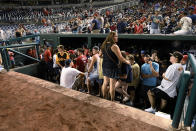 Spectators stand in the visiting team dugout during a stoppage in play due to an incident near the ballpark in the sixth inning of a baseball game between the Washington Nationals and the San Diego Padres, Saturday, July 17, 2021, in Washington. (AP Photo/Nick Wass)