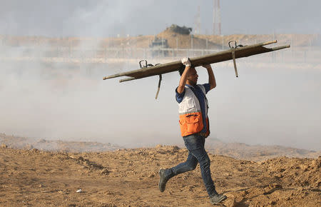 A medic carries stretcher as he runs during a protest where Palestinians demand the right to return to their homeland at the Israel-Gaza border, in the southern Gaza Strip August 3, 2018. REUTERS/Ibraheem Abu Mustafa