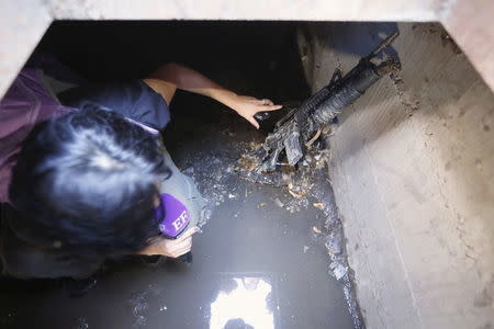 A television journalist points to a weapon found in a drain from where Joaquin "El Chapo" Guzman escaped before being captured at Jiquilpan Boulevard in Los Mochis, in Sinaloa state, Mexico, January 9, 2016. Mexico's government aims to fulfill a request from the United States to extradite the newly-recaptured drug lord Guzman to face drug trafficking charges, sources familiar with the situation said on Saturday. REUTERS/Edgard Garrido